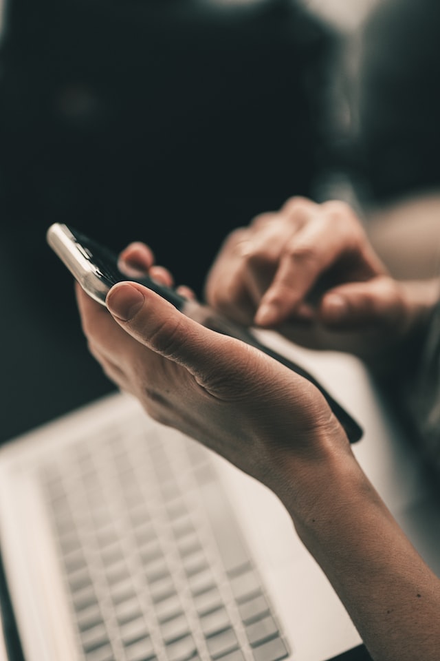 A photo of hands holding and using a mobile phone